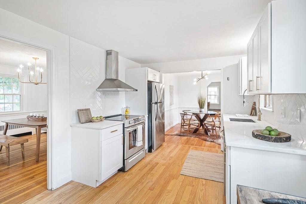 93 Meadowbrook Road Needham, MA 02492 - Photo 7 of 34 a kitchen with stainless steel appliances granite countertop a stove top oven a sink a dining table and chairs with wooden floor