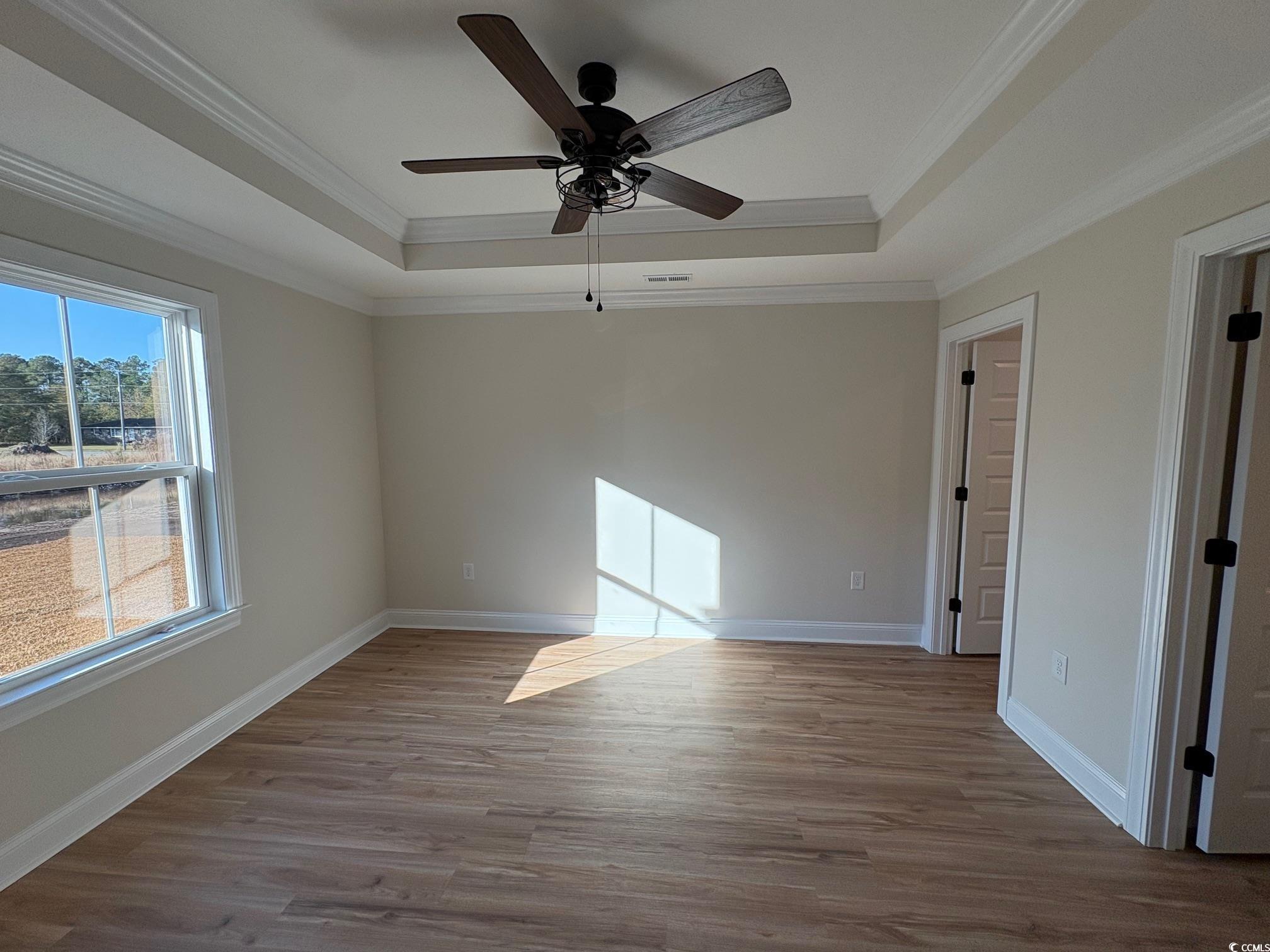 1721 Southern Crest Drive Loris, SC 29569 - Photo 2 of 16 Unfurnished room with a raised ceiling, light wood finished floors, ornamental molding, and a ceiling fan