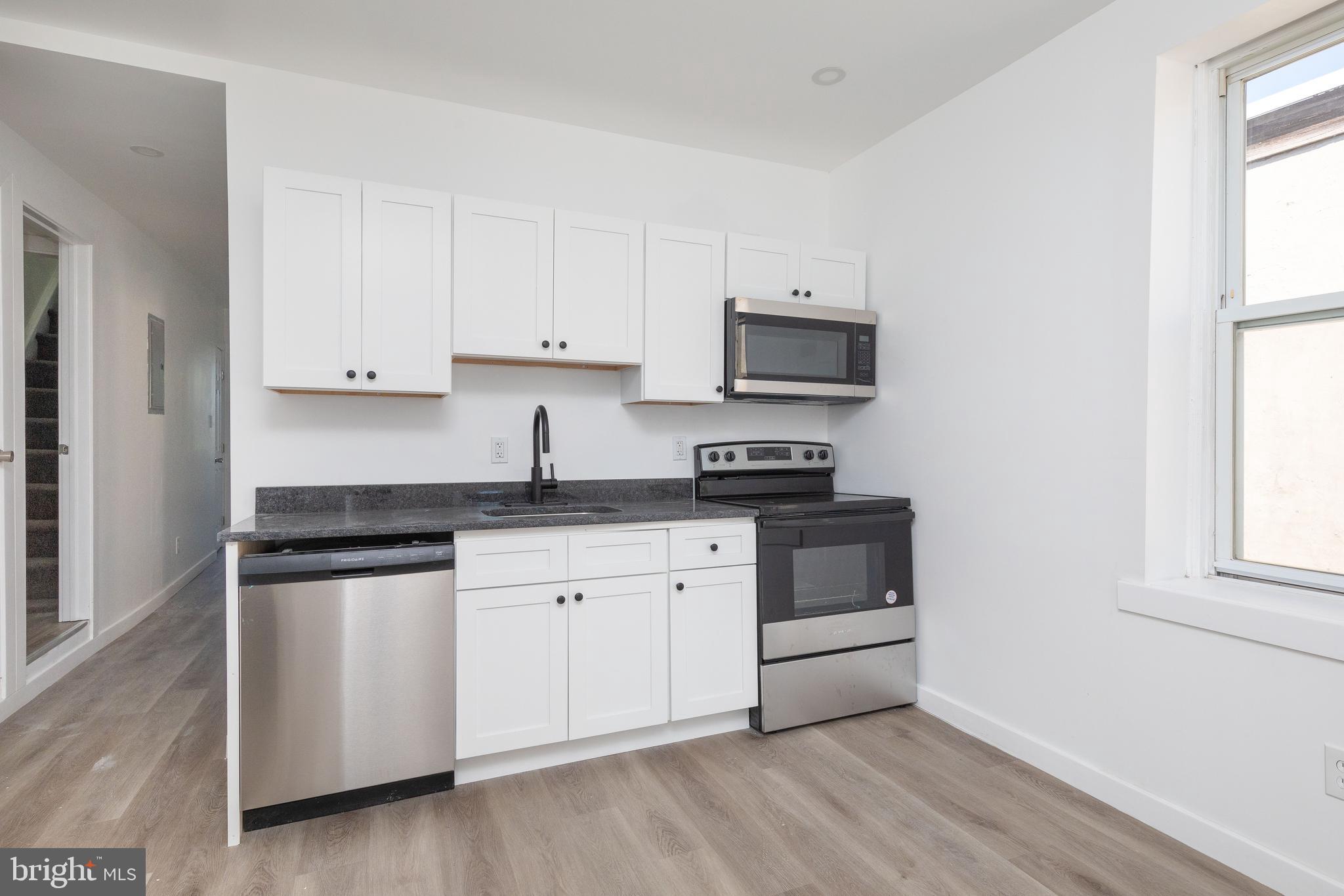 1841 North 33rd Street Philadelphia, PA 19121 - Photo 6 of 29 a kitchen with granite countertop white cabinets and white appliances