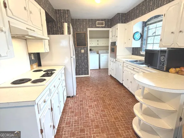 a large white kitchen with a stove a sink dishwasher and a refrigerator