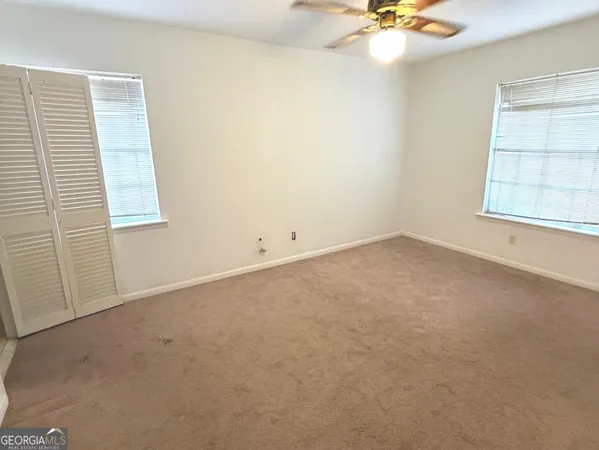 an empty room with a window and a ceiling fan