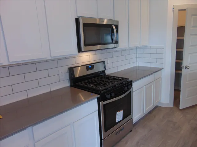 a kitchen with granite countertop a stove and a microwave