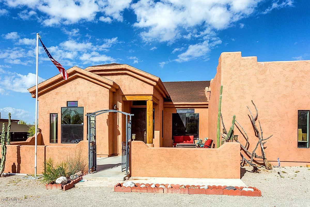 4180 North Wolverine Pass Road Apache Junction, AZ 85119 - Photo 1 of 17 a view of a white house with large windows and a small yard