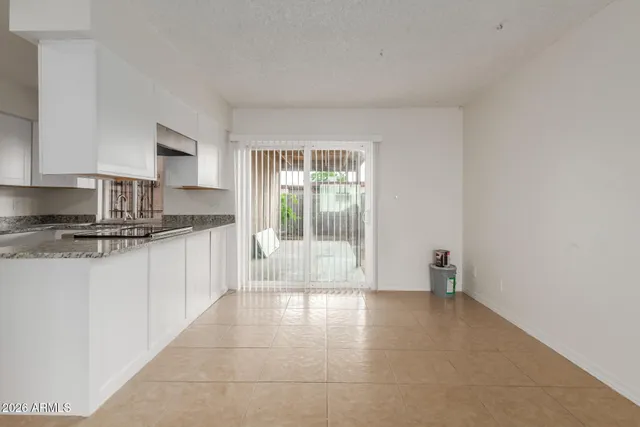 a view of kitchen with stainless steel appliances granite countertop white cabinets and window