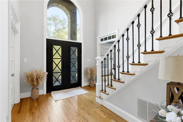 a kitchen with stainless steel appliances granite countertop a refrigerator a stove top oven a sink dishwasher and white cabinets with wooden floor