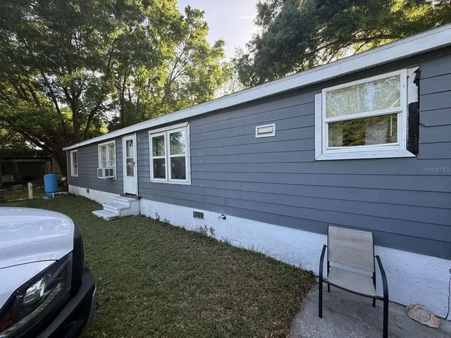 a view of a backyard with couches plants and large trees