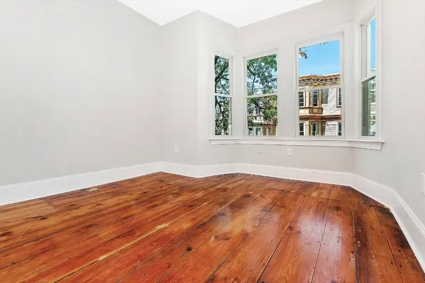 a view of a bedroom with wooden floor and a window