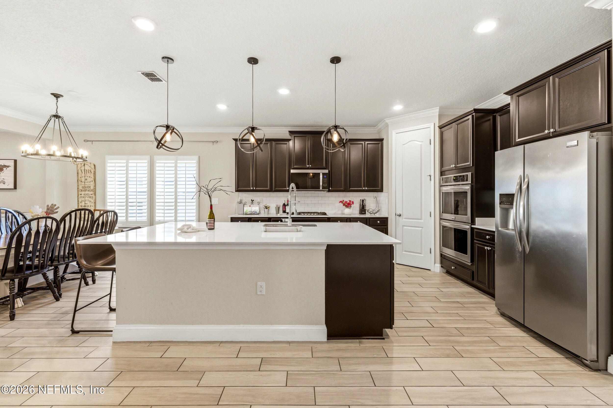 113 Howell Court St. Augustine, FL 32092 - Photo 24 of 63 a kitchen with stainless steel appliances kitchen island granite countertop a refrigerator a stove a sink a oven with a dining table and chairs