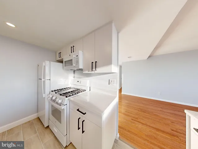 a kitchen with stainless steel appliances a stove and white cabinets