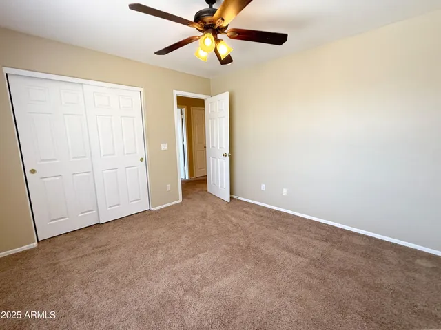 an empty room with closet and a chandelier fan