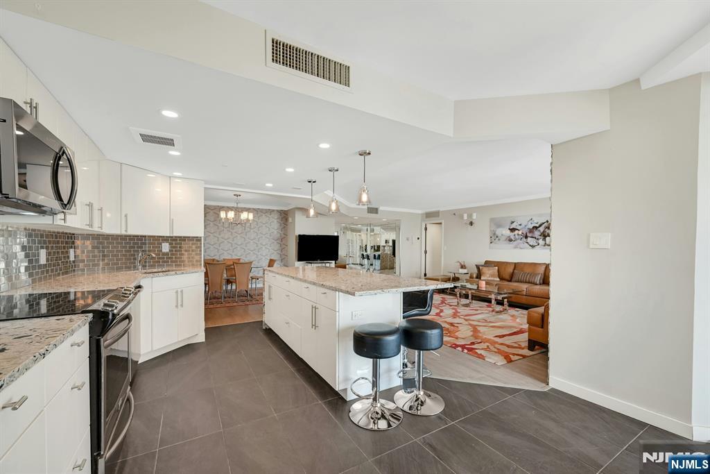 245 Prospect Avenue, Unit 12B Hackensack, NJ 07601 - Photo 11 of 33 a large white kitchen with cabinets and chairs