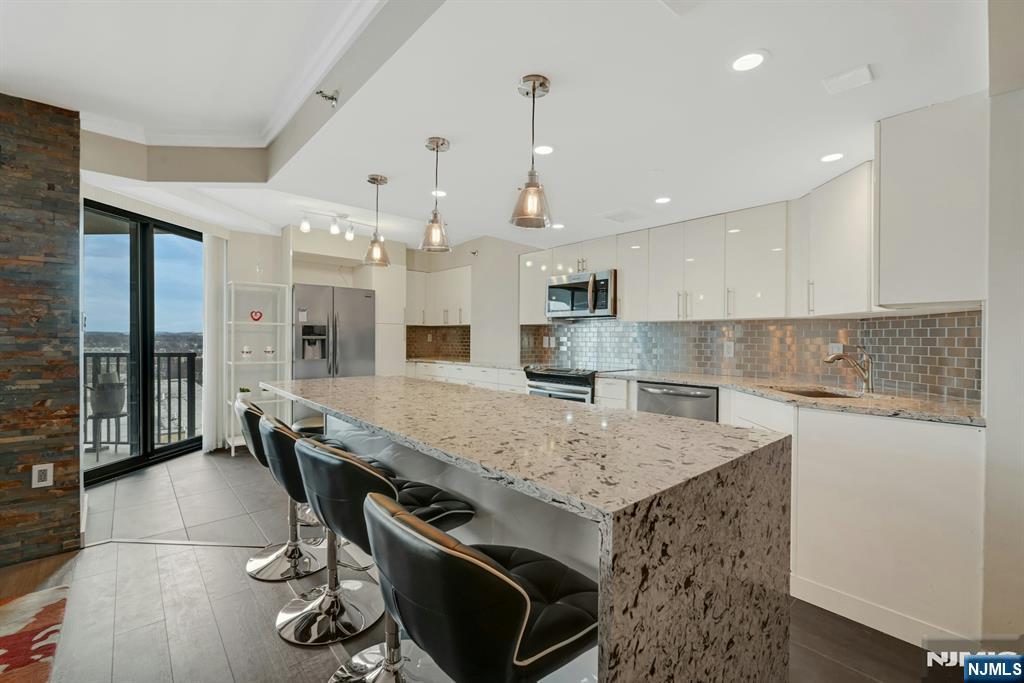 245 Prospect Avenue, Unit 12B Hackensack, NJ 07601 - Photo 9 of 33 a kitchen with a stove a refrigerator a sink dishwasher with a dining table and chairs