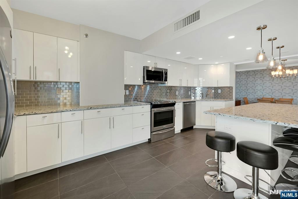245 Prospect Avenue, Unit 12B Hackensack, NJ 07601 - Photo 10 of 33 a kitchen with stainless steel appliances granite countertop a sink and cabinets