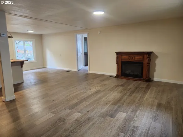 a view of empty room with wooden floor and fireplace