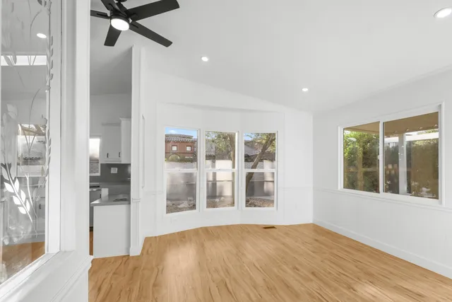 a view of empty room with wooden floor and fan