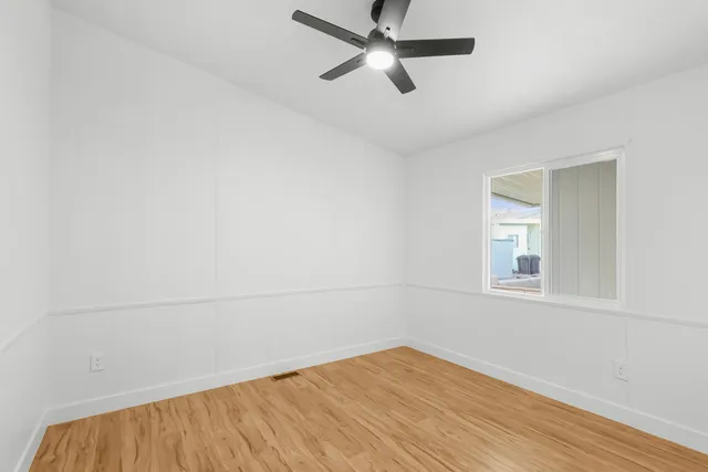 an empty room with a window and a ceiling fan