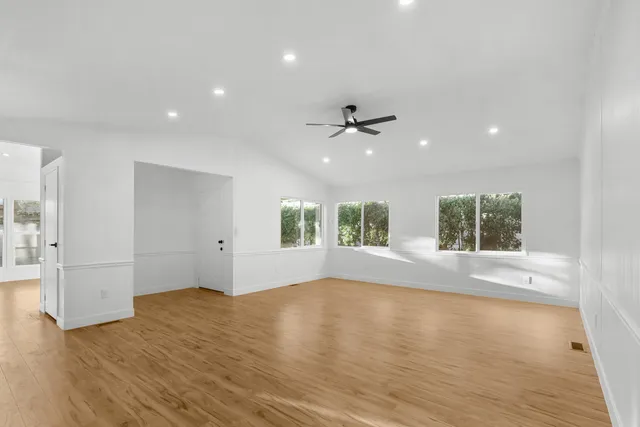 a view of an empty room with a window and wooden floor