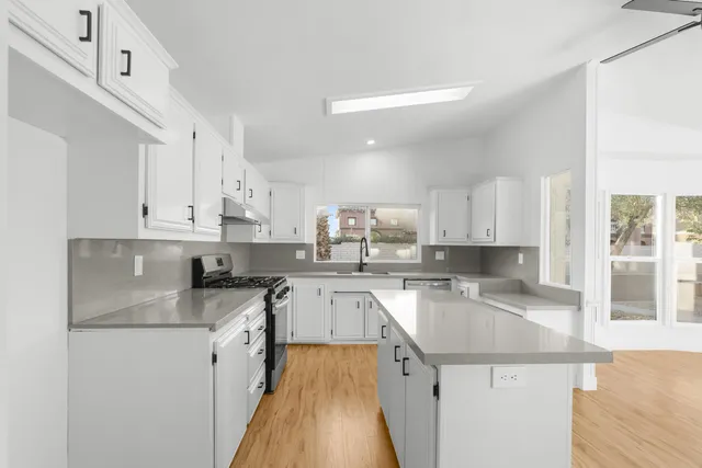 a kitchen with granite countertop a sink a counter top space stainless steel appliances and cabinets