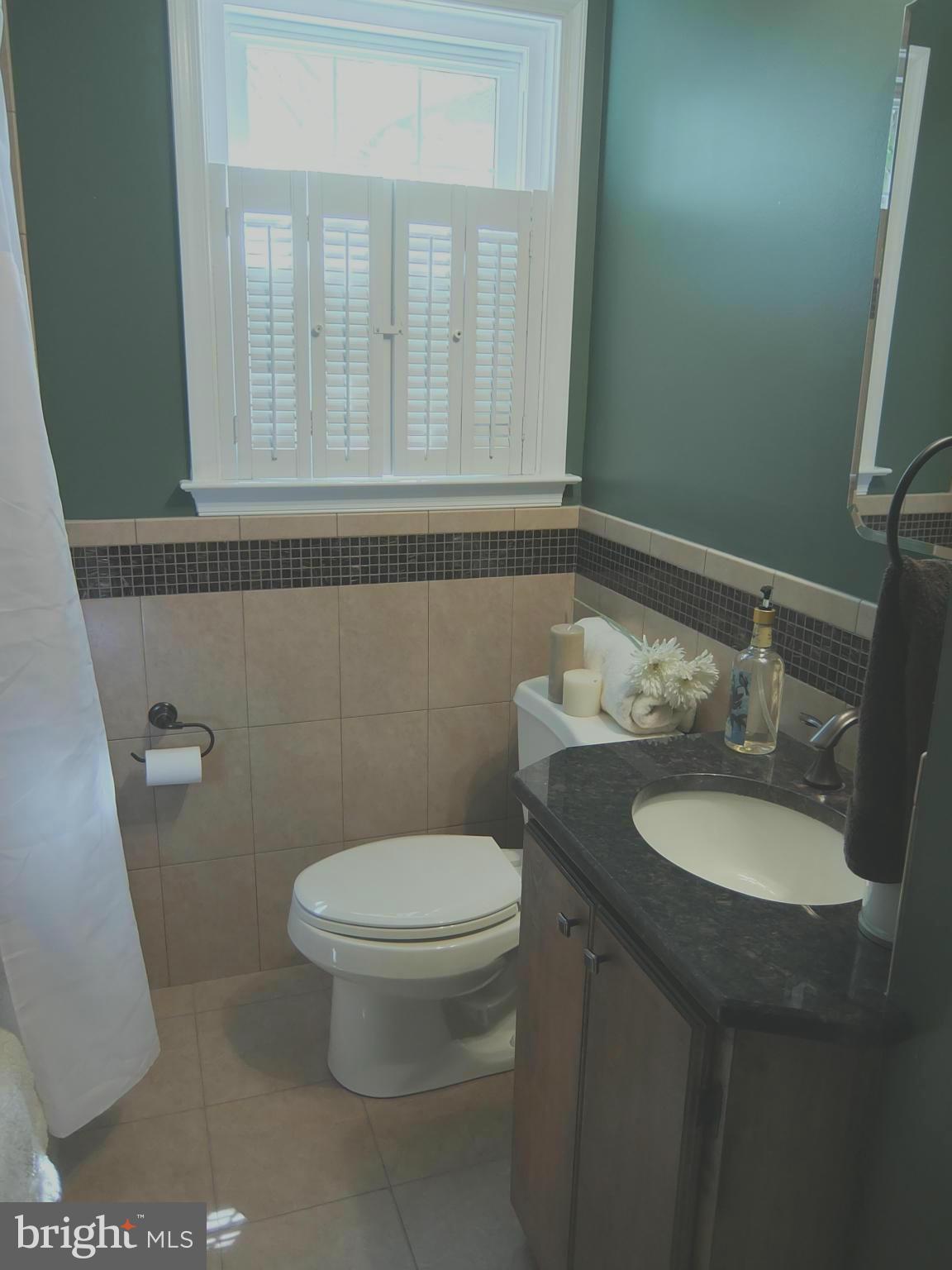 249 Gralan Road Baltimore, MD 21228 - Photo 20 of 25 a bathroom with a granite countertop toilet a sink and a mirror