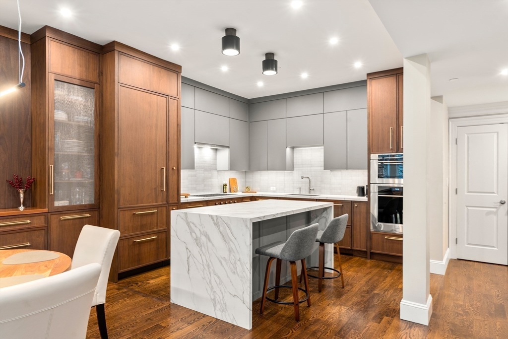 1471 Beacon Street, Unit 5 Brookline, MA 02446 - Photo 15 of 28 a kitchen with kitchen island stainless steel appliances a table and chairs in it
