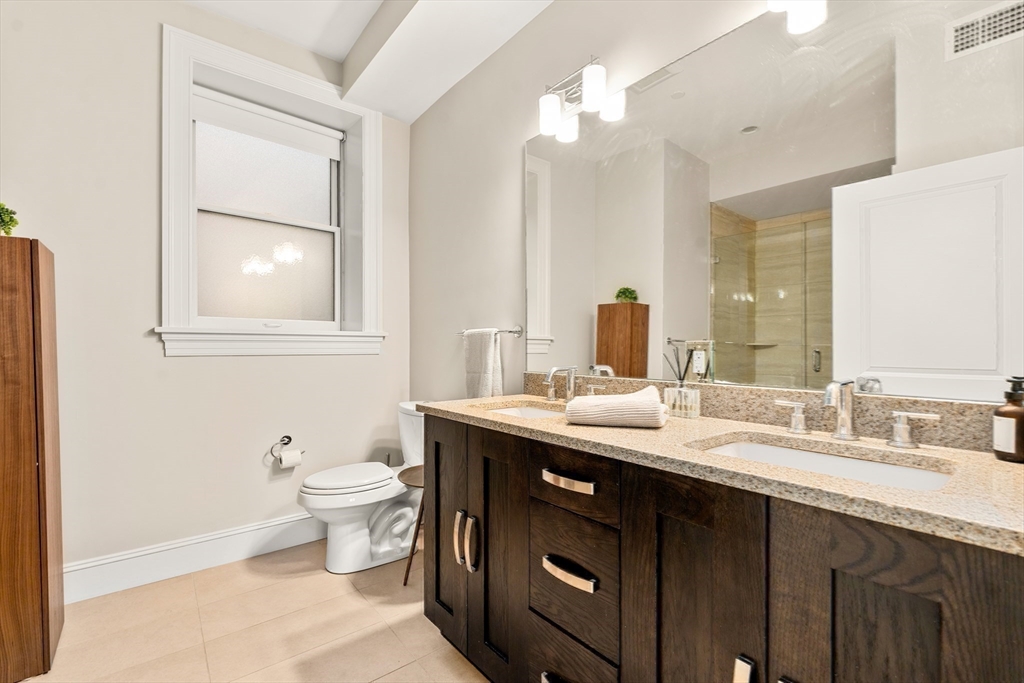 1471 Beacon Street, Unit 5 Brookline, MA 02446 - Photo 22 of 28 a bathroom with a granite countertop sink a toilet and a mirror