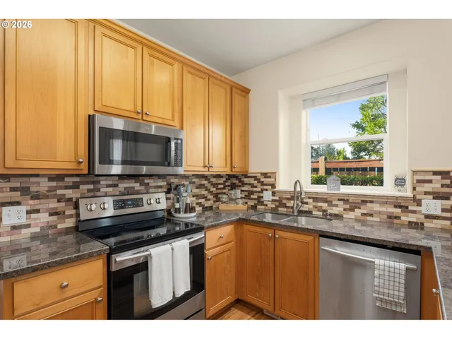 a kitchen with stainless steel appliances granite countertop a sink stove and microwave