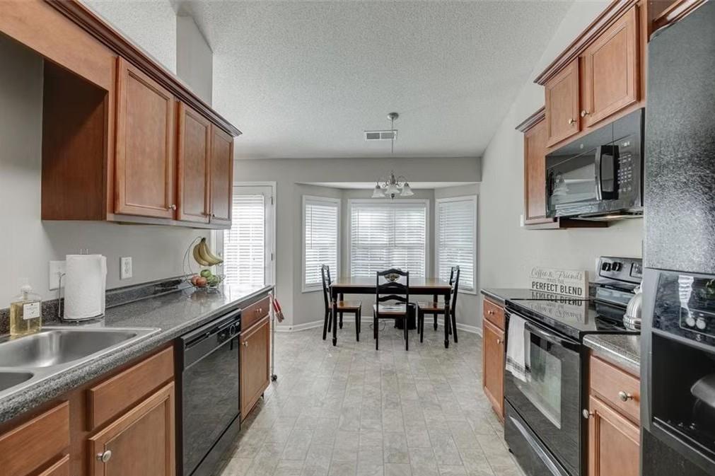 1281 Key Manor Lane Lawrenceville, GA 30045 - Photo 7 of 22 a kitchen with stainless steel appliances granite countertop a stove top oven a sink a dining table and chairs