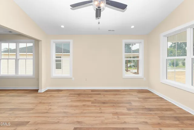 an empty room with wooden floor and windows