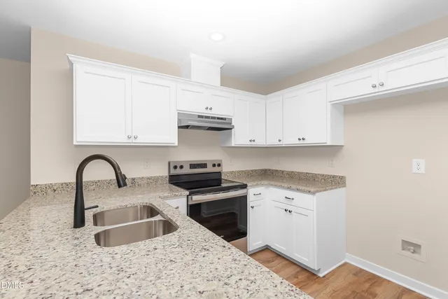 a kitchen with stainless steel appliances granite countertop a sink a stove a refrigerator a counter space and cabinets