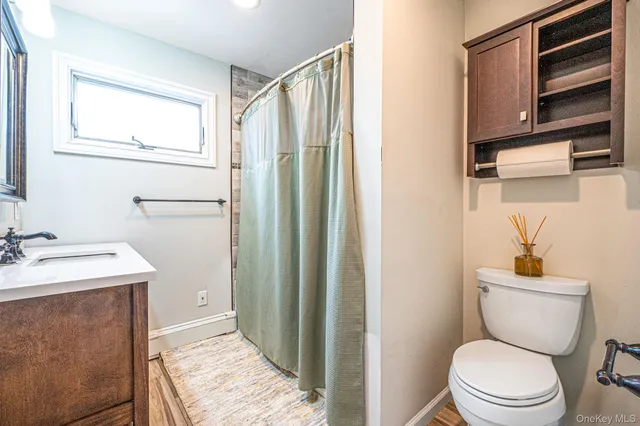 a bathroom with a sink a toilet a mirror and shower