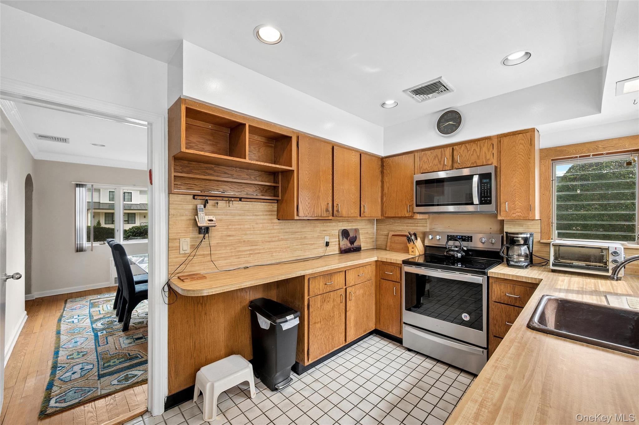 24 Allen Road Rockville Centre, NY 11570 - Photo 13 of 46 a kitchen with stainless steel appliances granite countertop a stove top oven a sink dishwasher a dining table and chairs with wooden floor