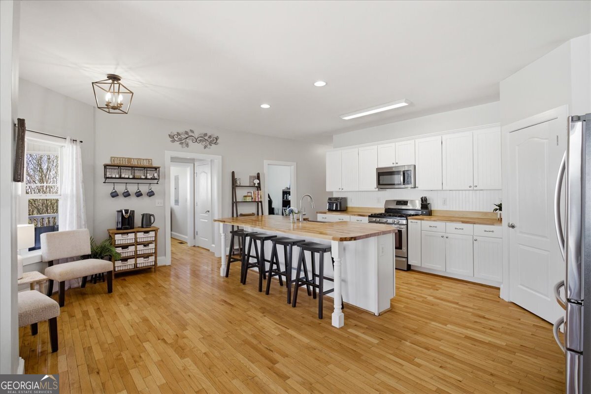 204 Staples Dairy Road Carrollton, GA 30116 - Photo 12 of 85 a open kitchen with stainless steel appliances kitchen island granite countertop a refrigerator a stove a sink a dining table and chairs with wooden floor