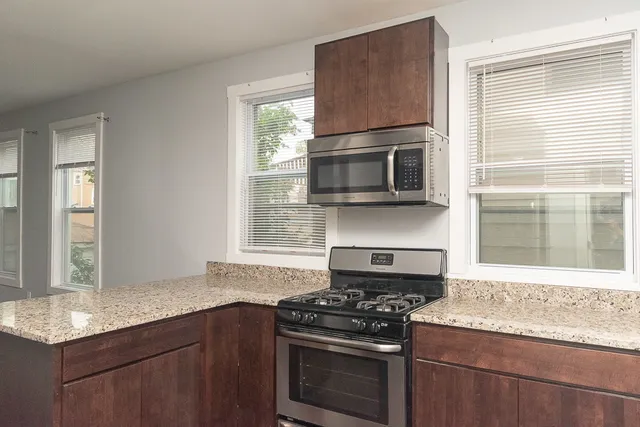 a kitchen with granite countertop cabinets stainless steel appliances and a window