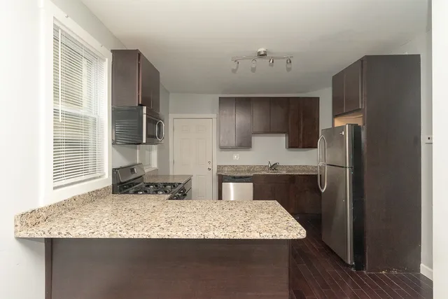 a kitchen with kitchen island granite countertop a sink refrigerator and cabinets