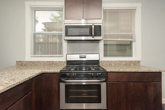 a kitchen with granite countertop a stove sink and microwave
