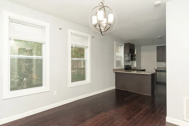 an empty room with wooden floor cabinet and windows