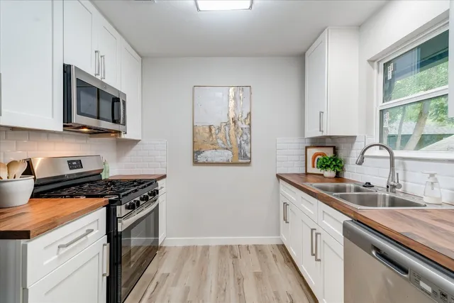 a kitchen with stainless steel appliances a sink a stove and microwave