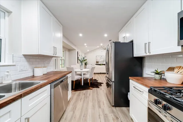 a kitchen with stainless steel appliances a sink dishwasher stove refrigerator and cabinets with wooden floor