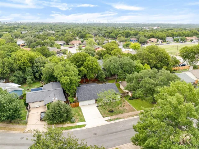 an aerial view of residential houses with outdoor space and trees