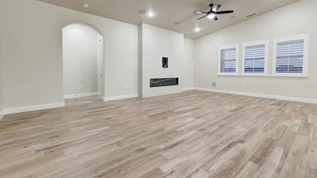 an empty room with wooden floor closet and windows