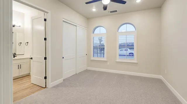 an empty room with windows and chandelier fan