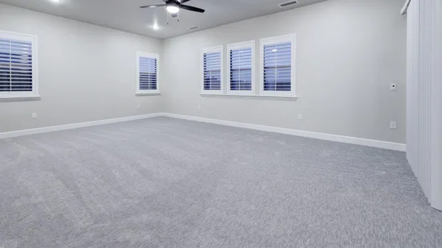 an empty room with a chandelier fan and windows