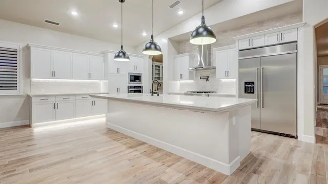 a large kitchen with granite countertop a large counter top a sink stainless steel appliances and cabinets