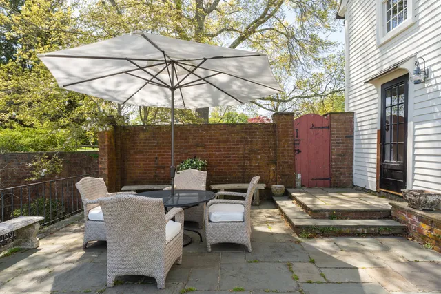 a view of a patio with couches table and chairs under an umbrella with a fire pit