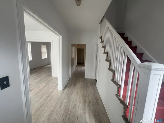 a view of a hallway with wooden floor and staircase