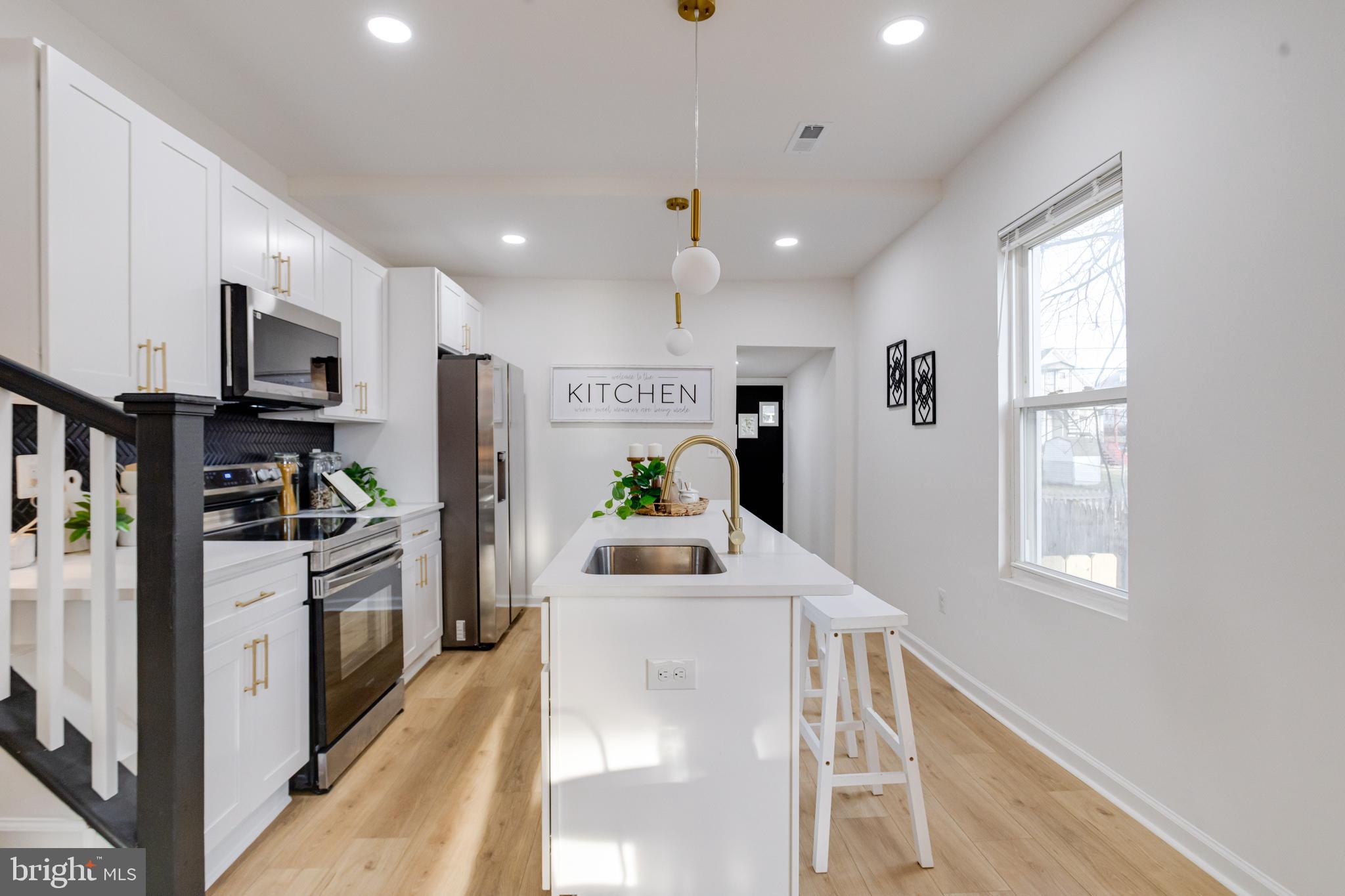 5805 Highgate Drive Baltimore, MD 21215 - Photo 18 of 69 a kitchen with stainless steel appliances kitchen island granite countertop a stove a sink a refrigerator white cabinets and wooden floor