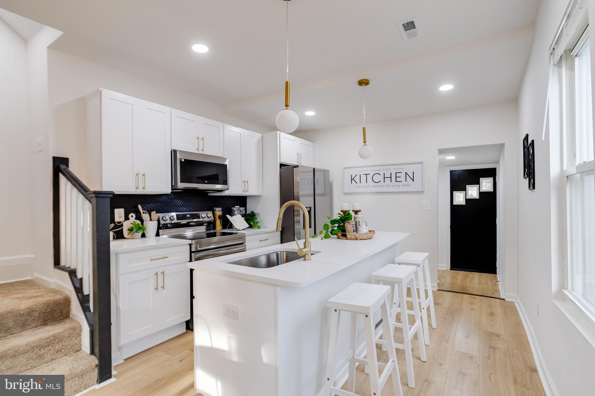5805 Highgate Drive Baltimore, MD 21215 - Photo 19 of 69 a kitchen with stainless steel appliances kitchen island granite countertop a refrigerator a stove top oven a sink dishwasher and white cabinets with wooden floor
