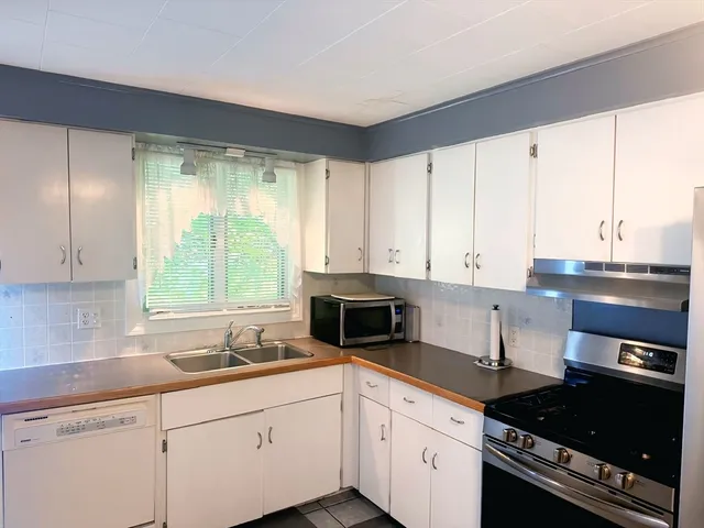 a kitchen with granite countertop a sink a stove and cabinets