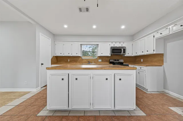 a kitchen with granite countertop white cabinets and stainless steel appliances