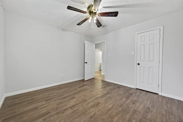 a view of an empty room with window a ceiling fan and wooden floor